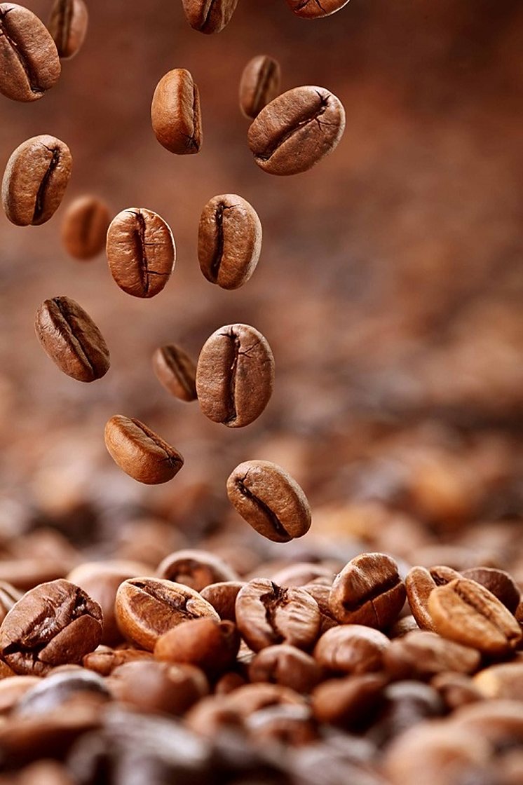 Roasted coffee beans falling onto a pile of beans