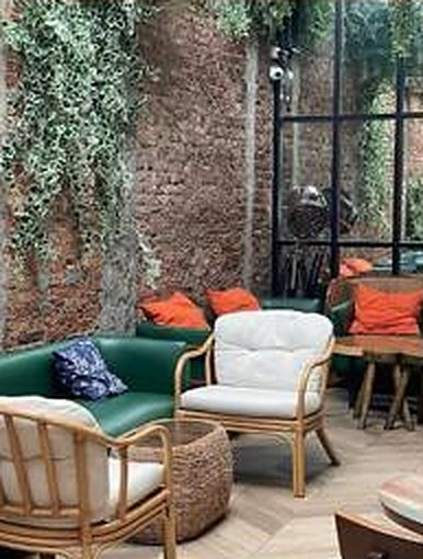 Lounge chairs and green sofa by a plant-covered brick wall